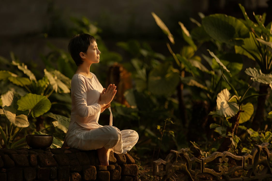 Mujer meditando al amanecer en un jardín - psicología transpersonal