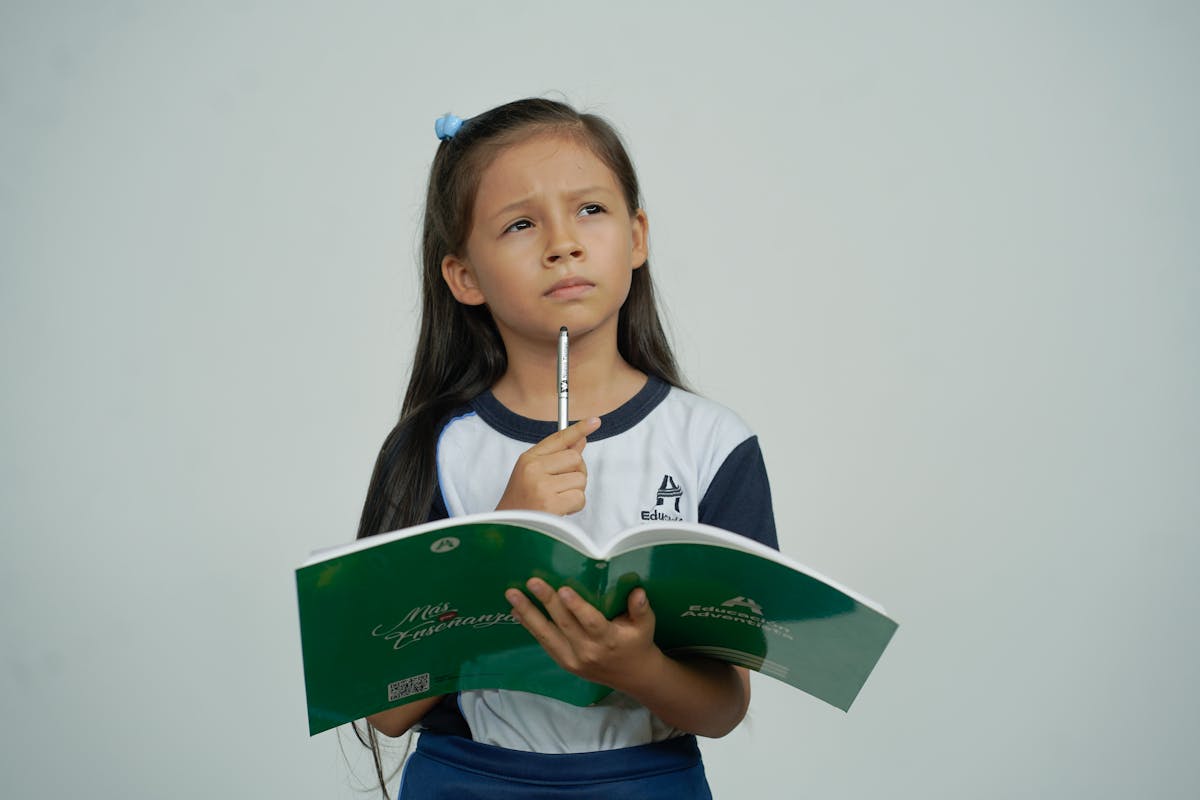 Niña estudiante pensando y sosteniendo un cuaderno