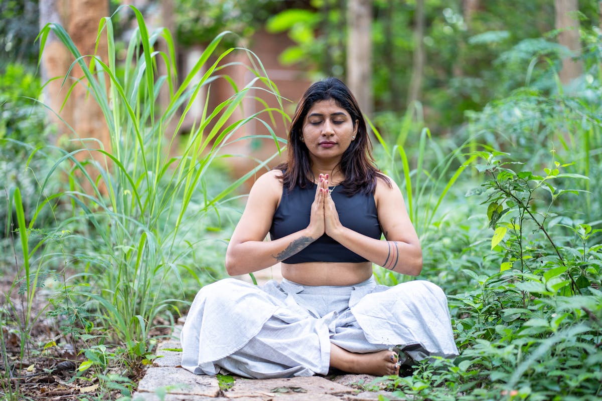 Mujer meditando en un jardín exuberante, encontrando paz interior